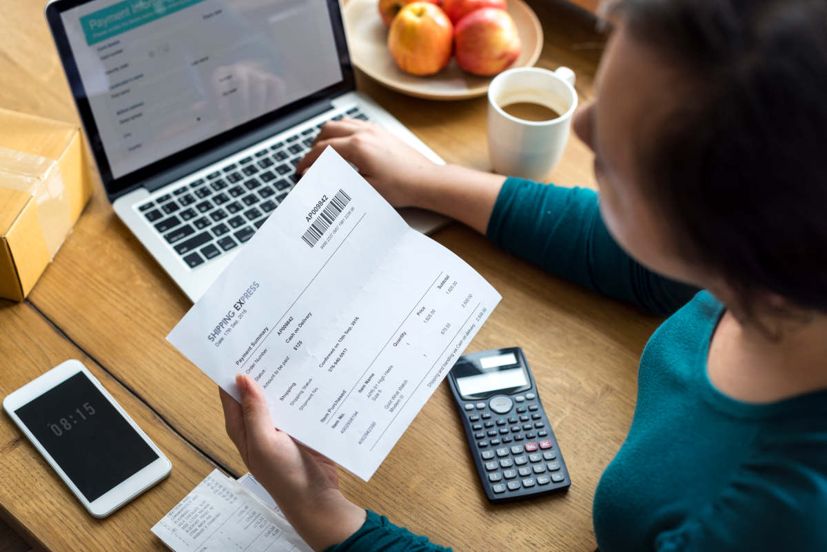  Profissional organizando finanças de empresa, revisando notas fiscais e utilizando calculadora para controle contábil